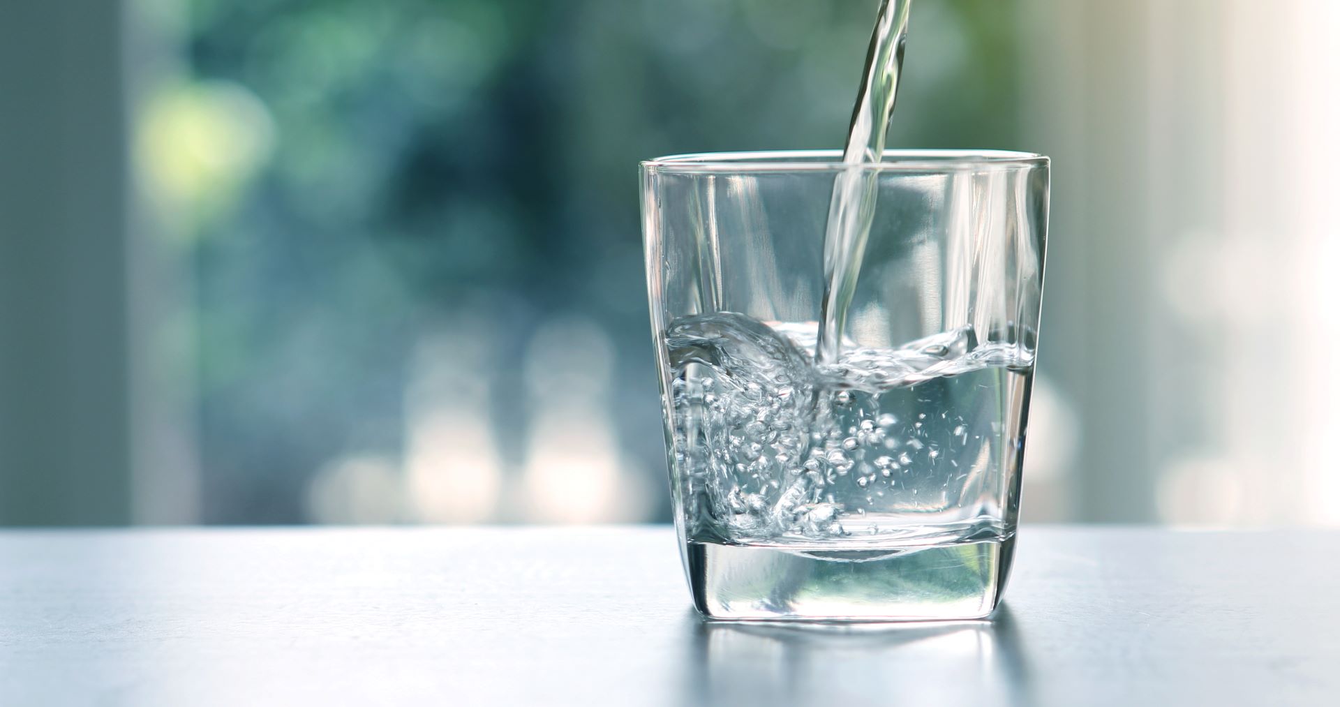 Glas wird mit klarem Wasser gefüllt
