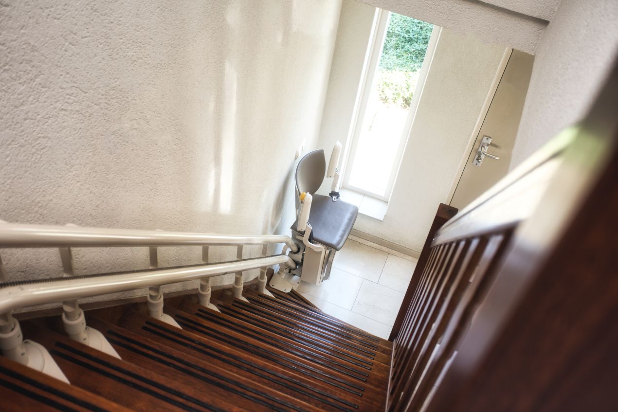 Treppe Lift installiert in einem schmalen Treppenhaus mit Holzstufen fuer barrierefreies Wohnen