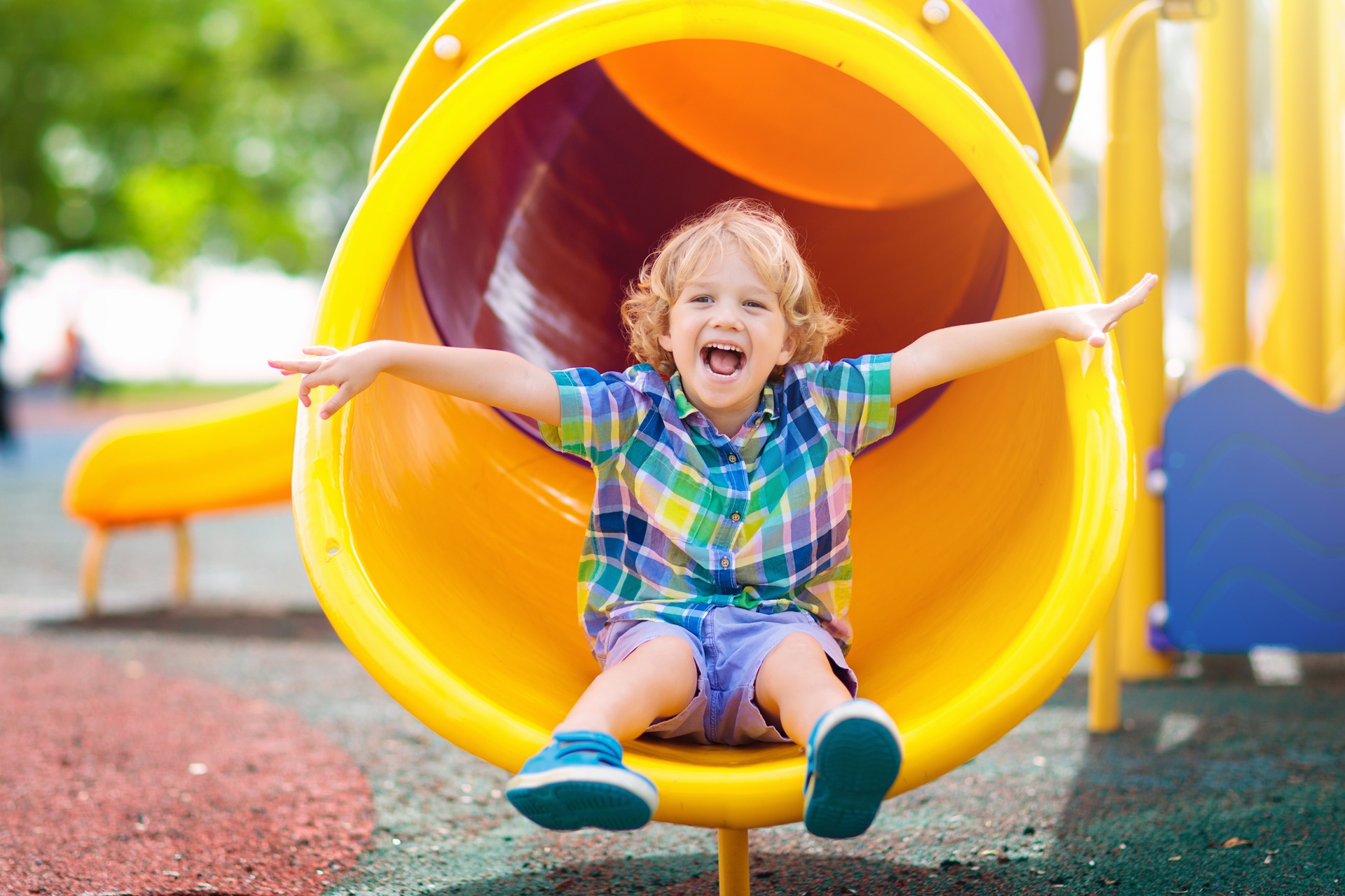 Kind rutscht lachend aus Rutsche | Spielplatzgeräte
