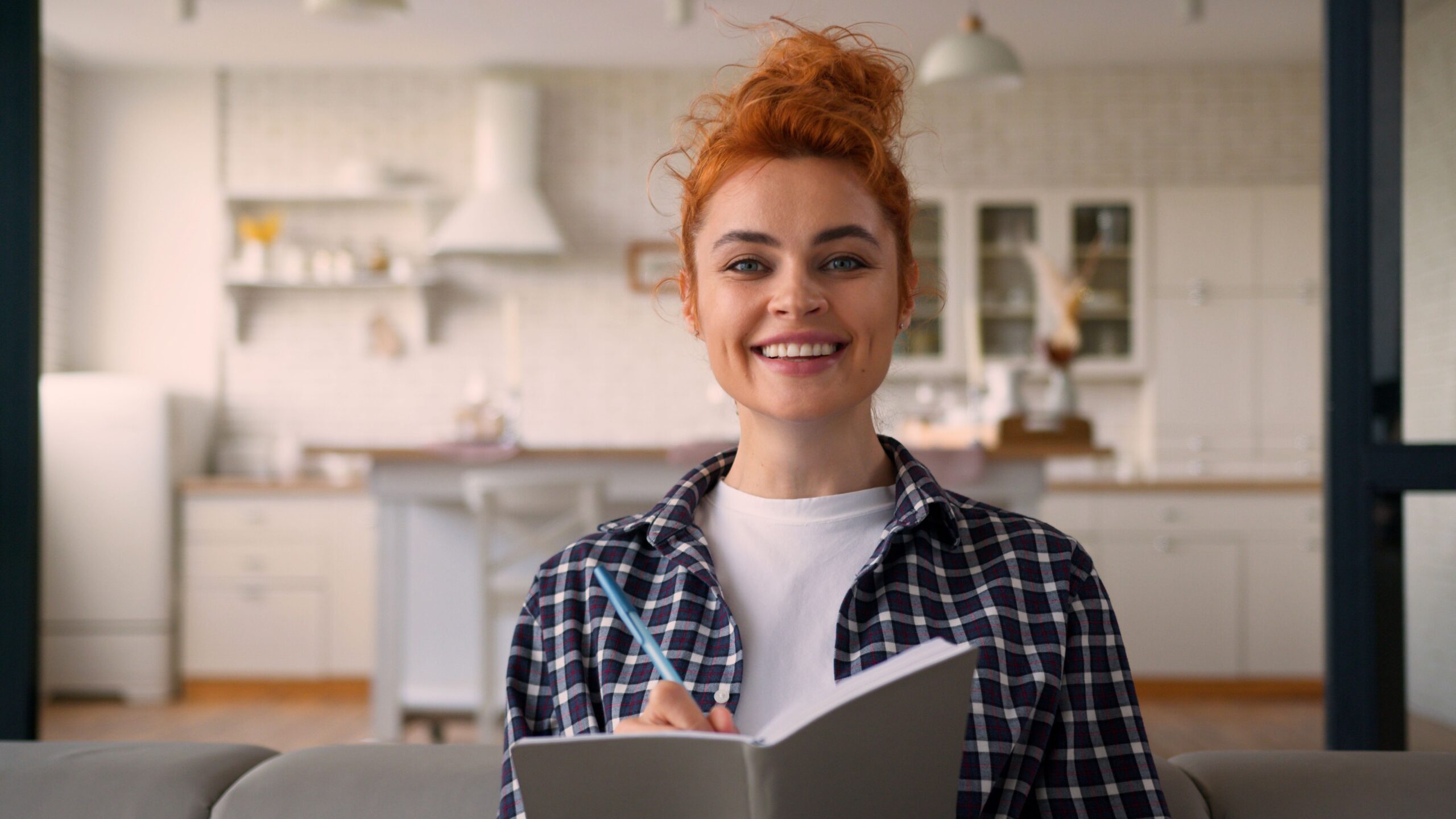 Frau erstellt Checkliste für Kauf eines Wasserfilters für Leitungswasser in moderner Küche